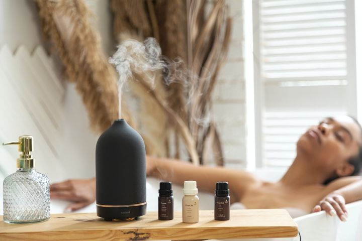 Aromatherapy - a woman laying in a bathtub next to a bottle of essential oils